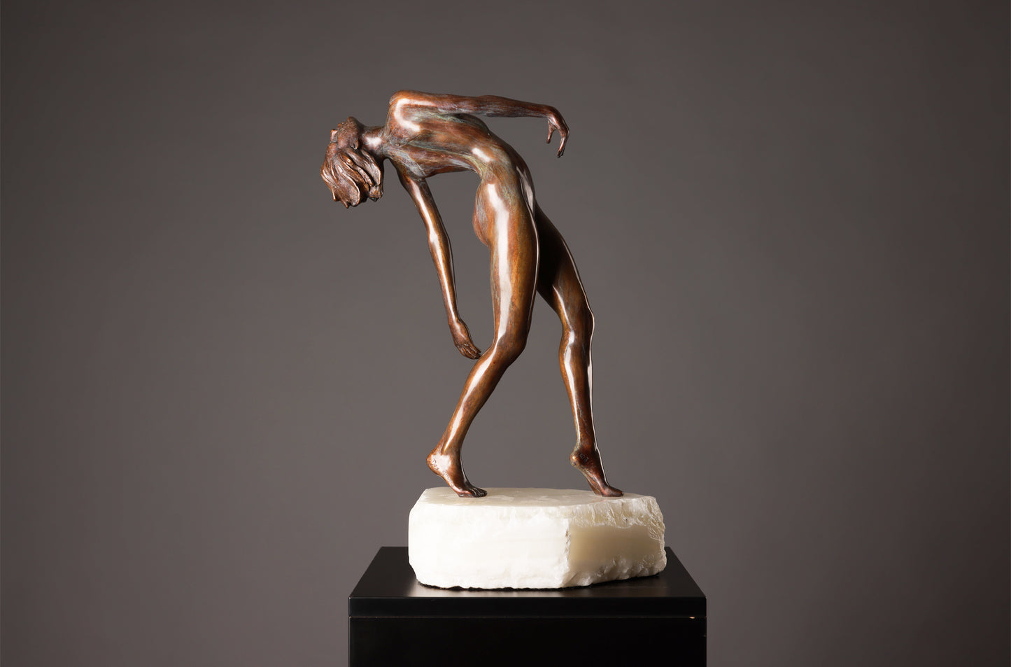 Bronze sculpture of a nude figure on a gray background