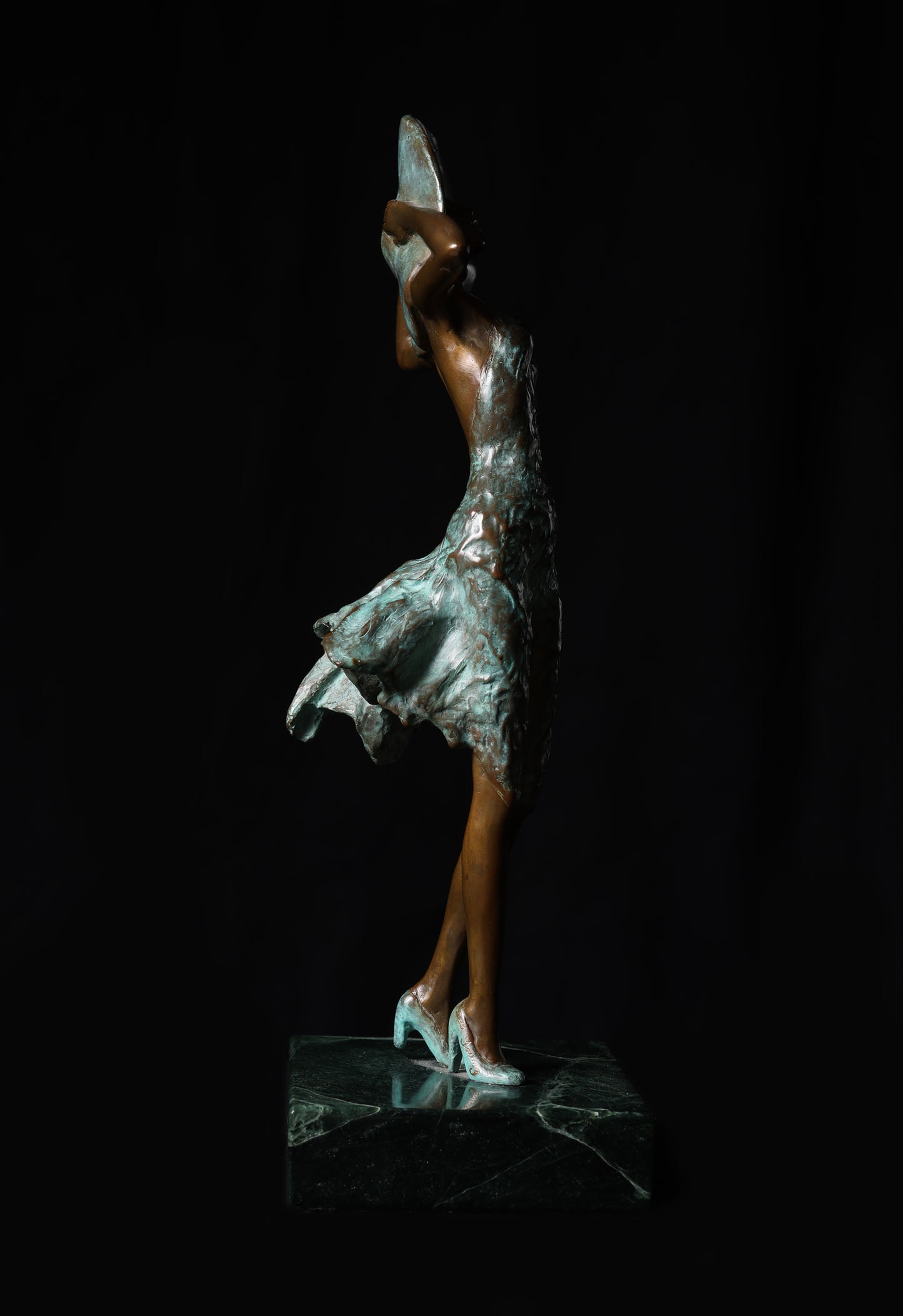 Bronze sculpture of a dancer with a silver skirt on a black background