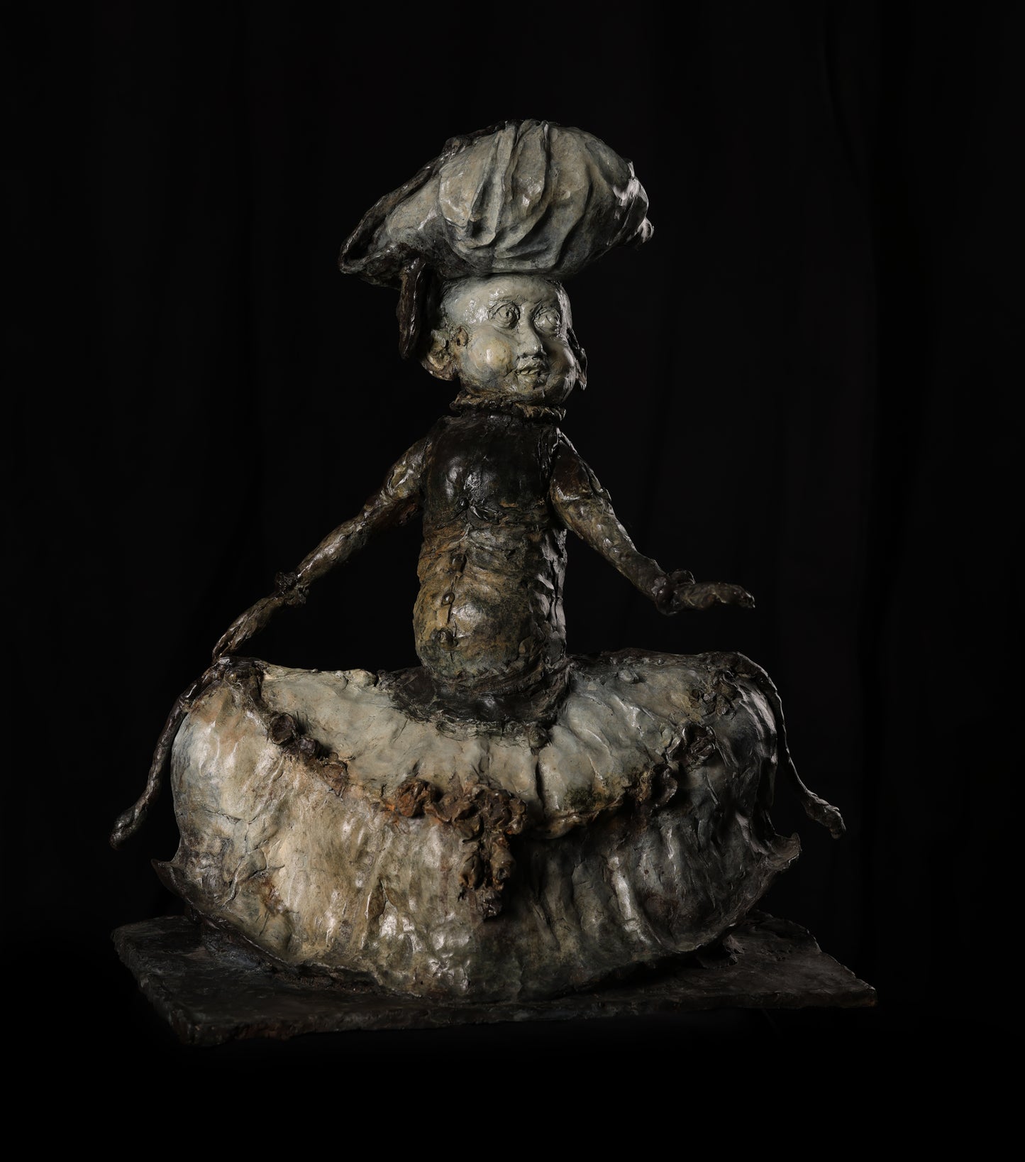 Metallic sculpture of a figure with a hat on a black background