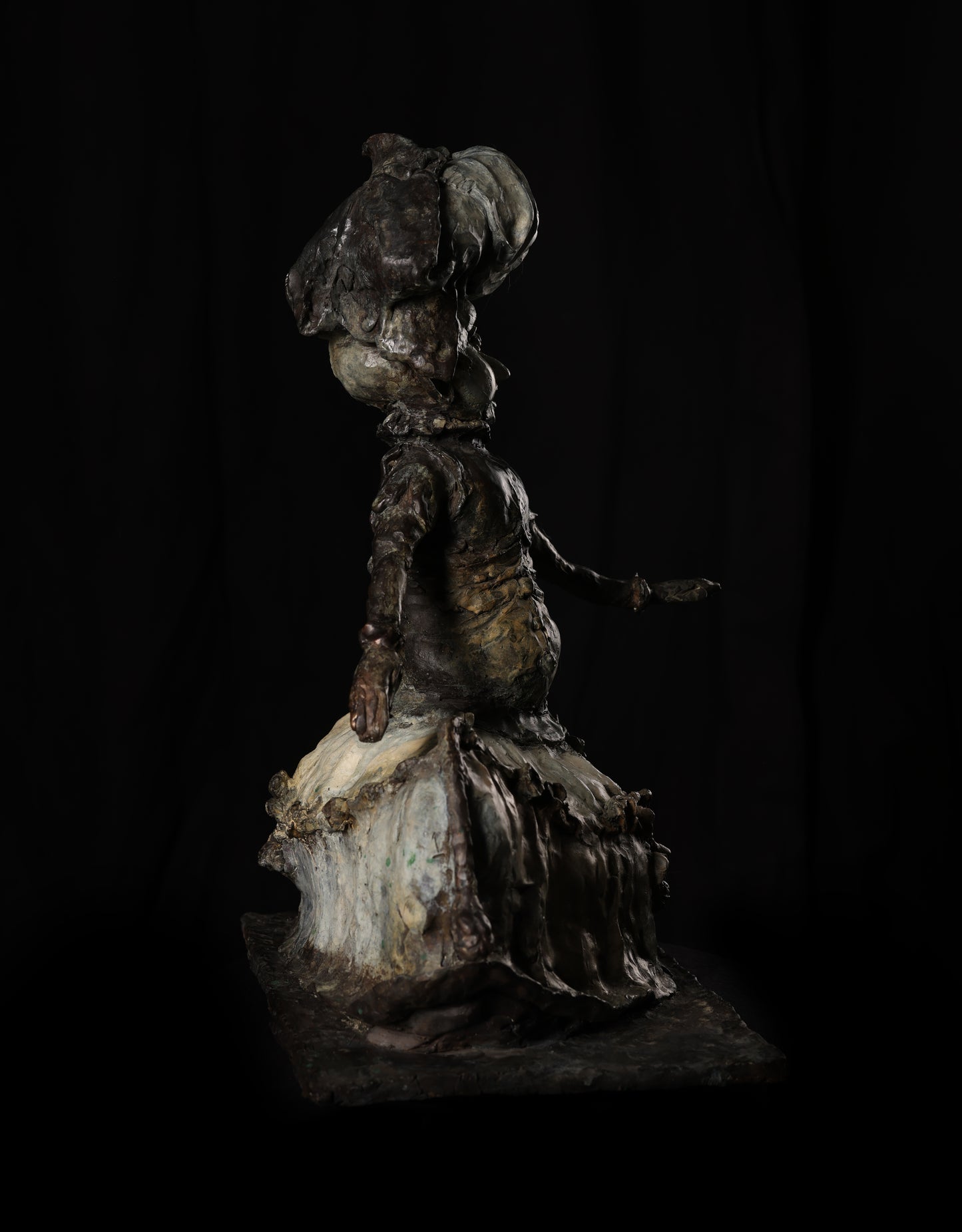 Metallic sculpture of a figure with a hat on a dark background