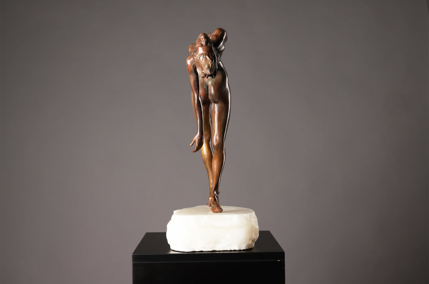 Bronze sculpture of a dancer on a marble base against a gray background