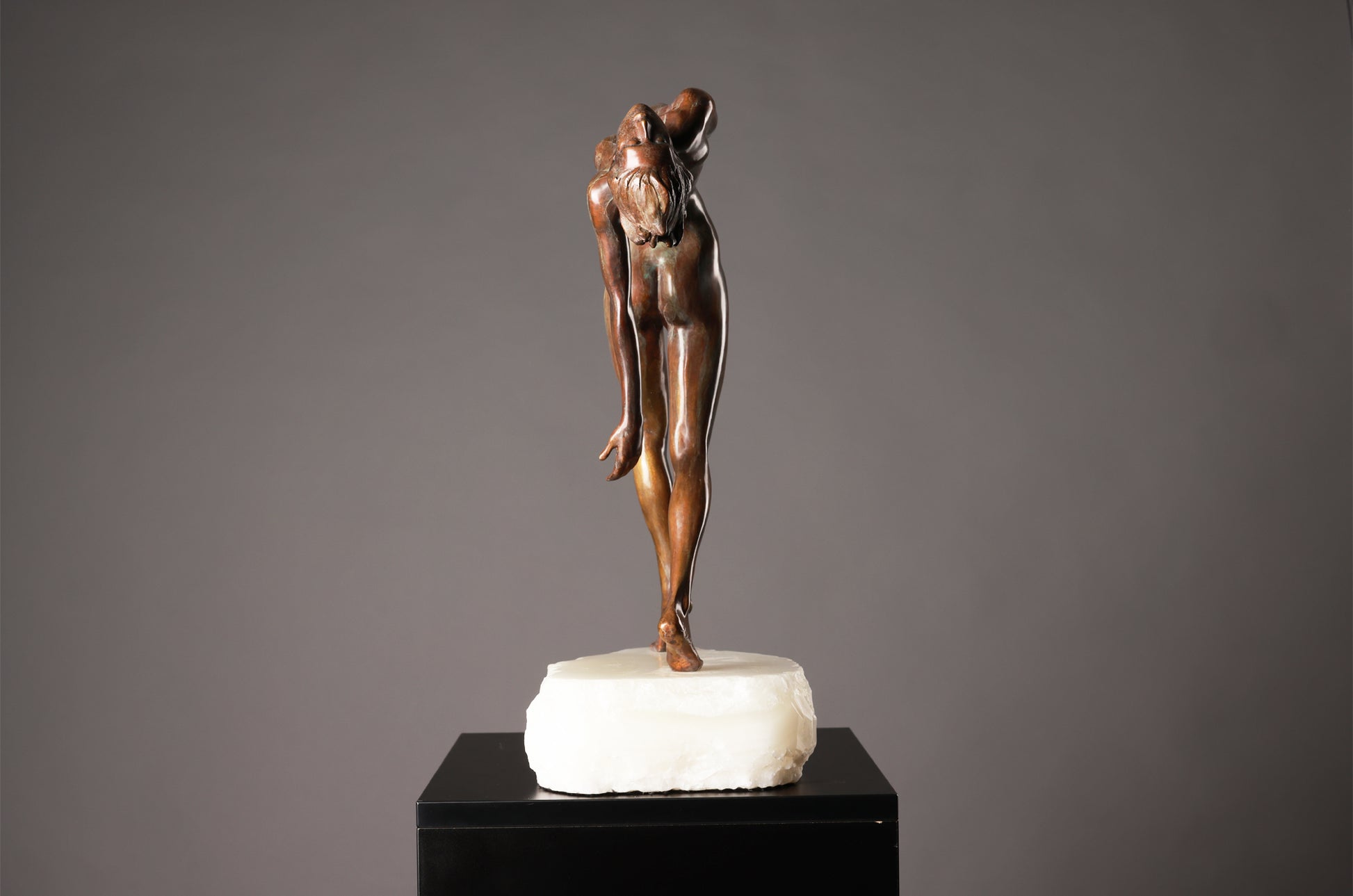 Bronze sculpture of a dancer on a marble base against a gray background