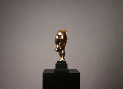 Gold bull statue on a black pedestal against a gray background