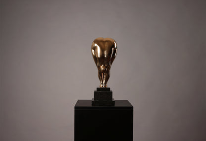 Bronze sculpture of a bull on a black pedestal against a gray background
