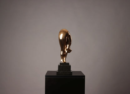 Gold bull statue on a black pedestal against a gray background