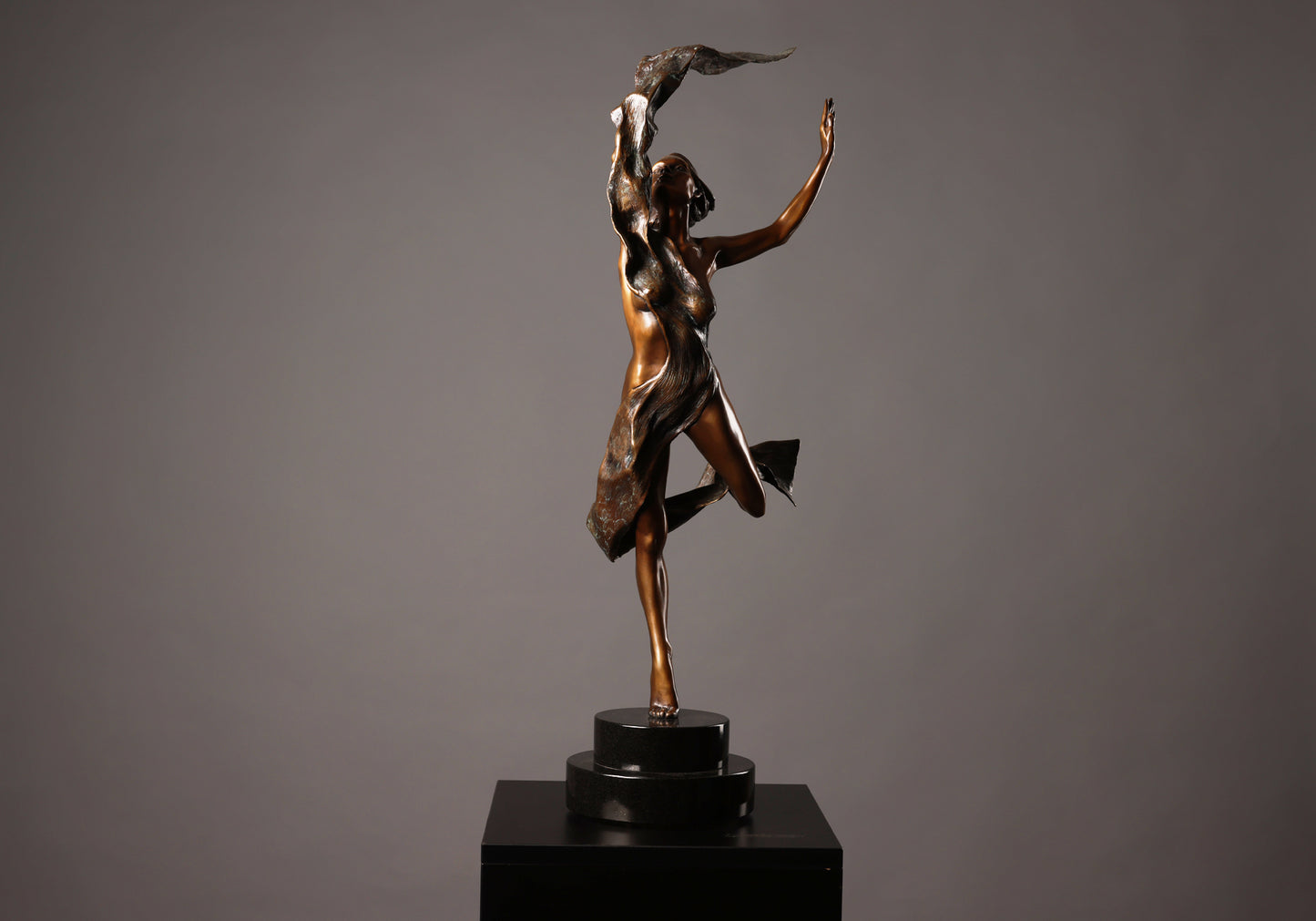Bronze sculpture of a dancer on a gray background