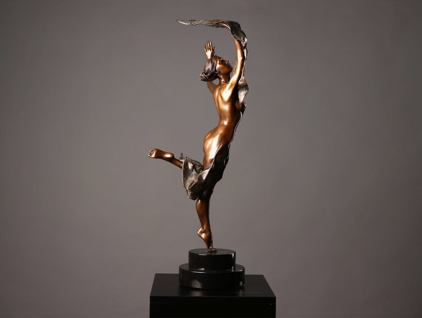 Bronze sculpture of a dancer on a black base against a gray background