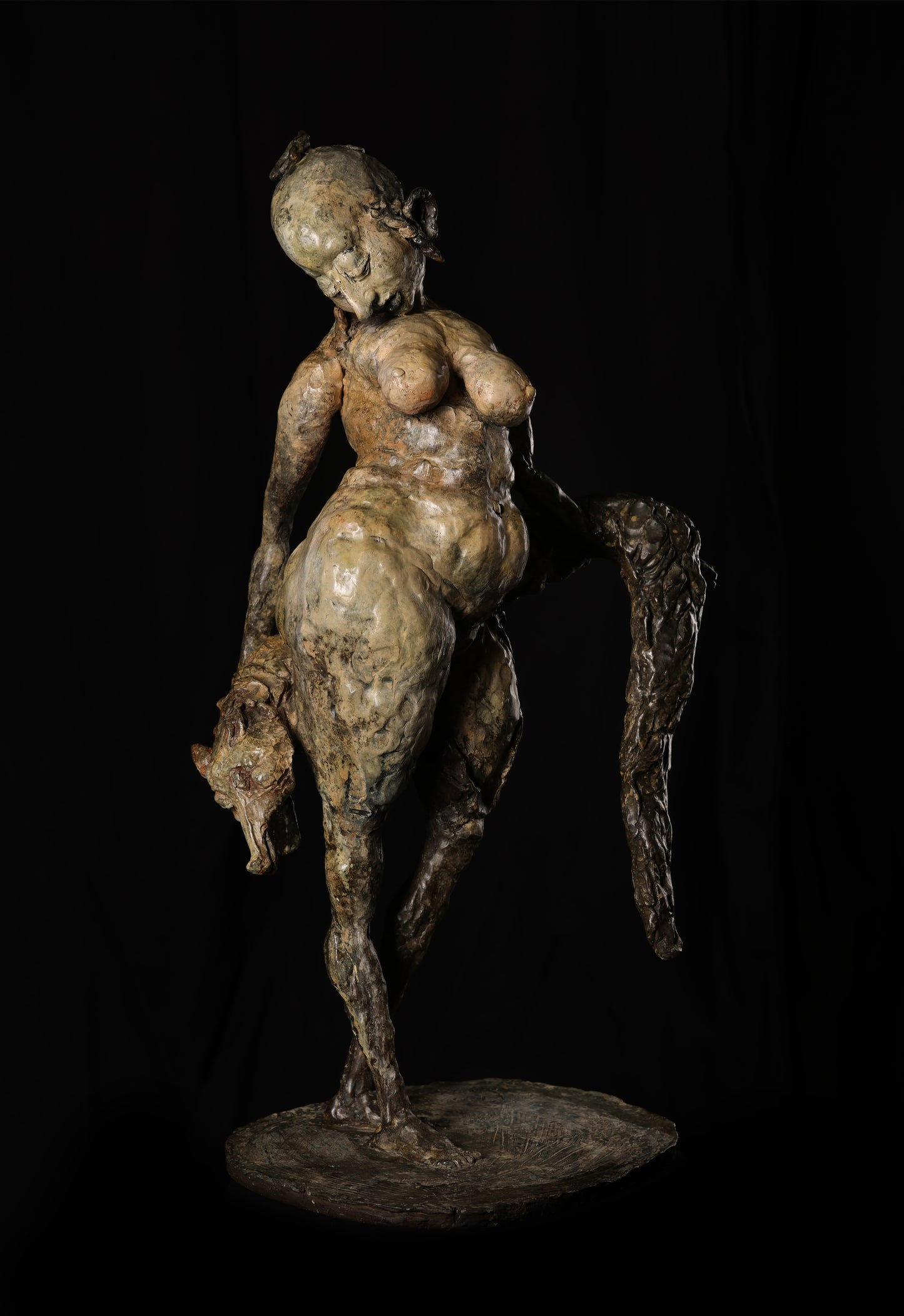 Bronze sculpture of a nude figure riding a horse on a black background