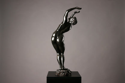 Statue of a nude figure on a pedestal against a gray background