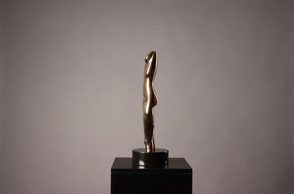 Gold sculpture on a black pedestal against a gray background