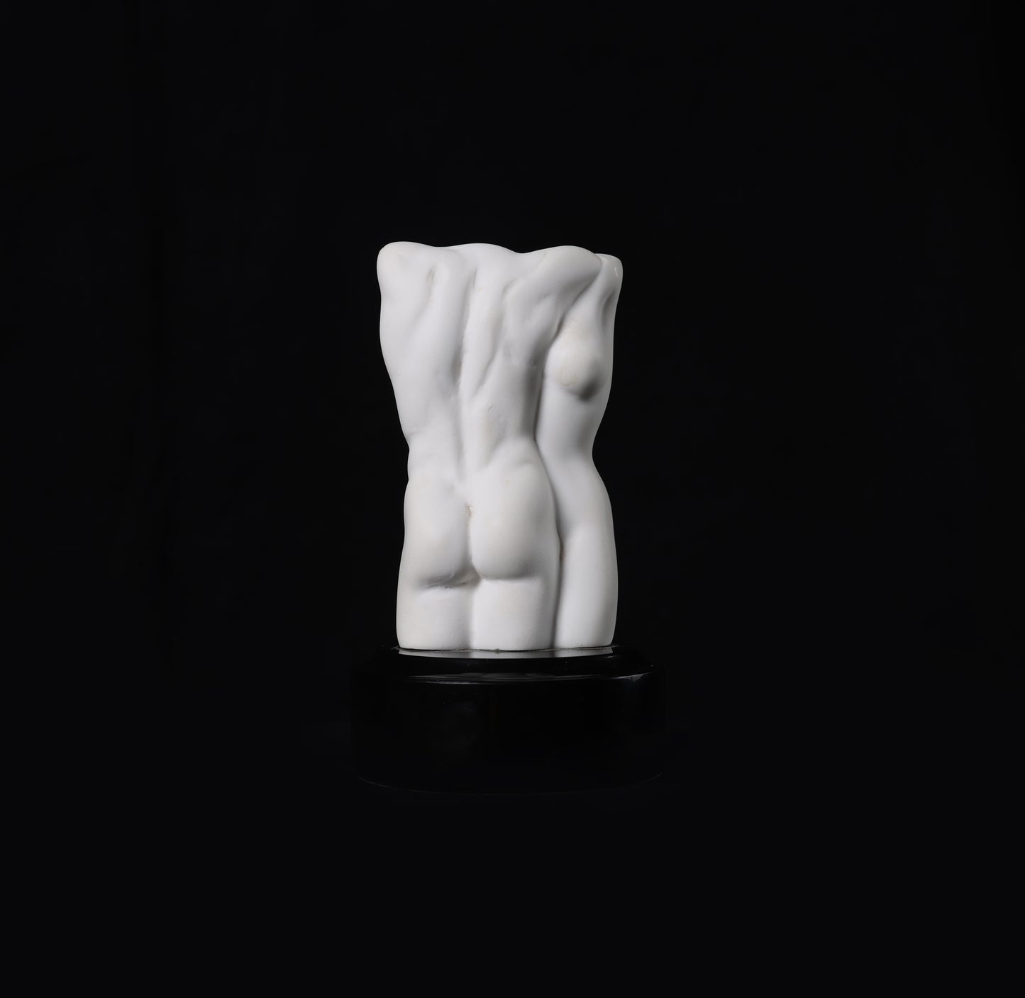 White ceramic sculpture of a torso on a black background