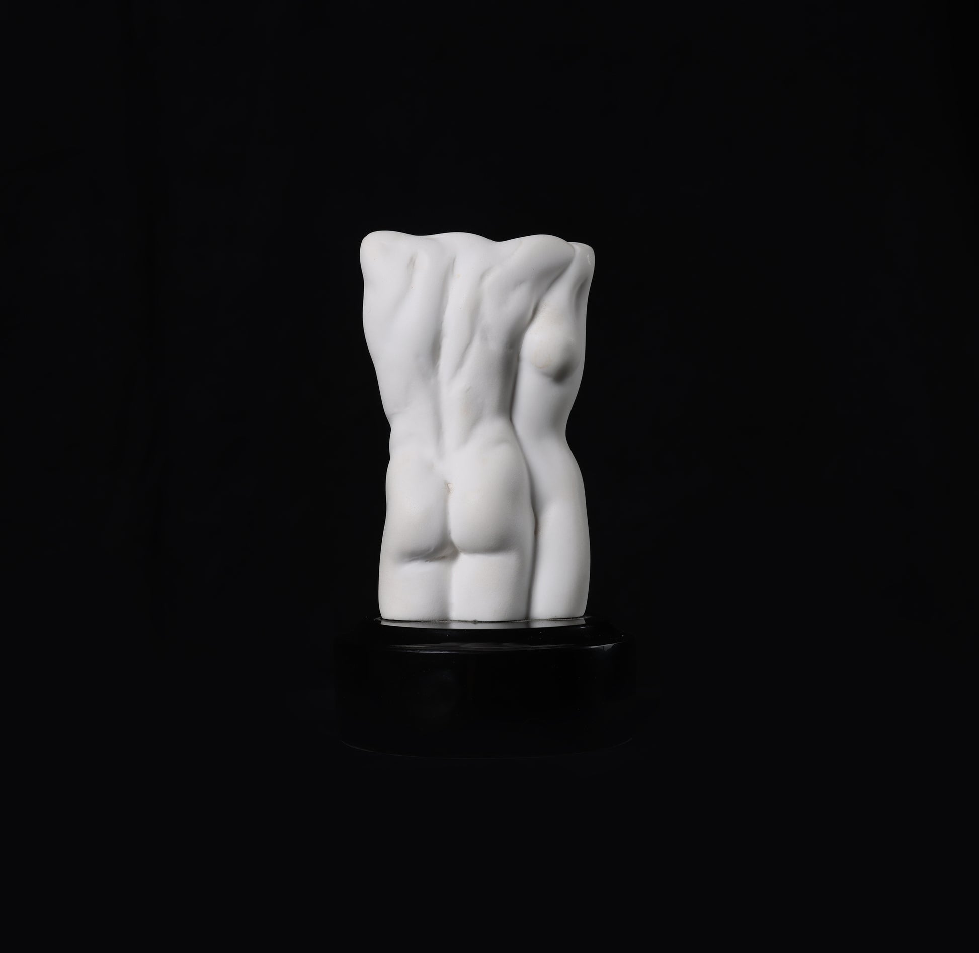White ceramic sculpture of a torso on a black background