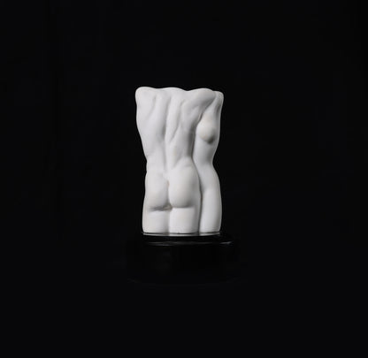 White ceramic sculpture of a torso on a black background