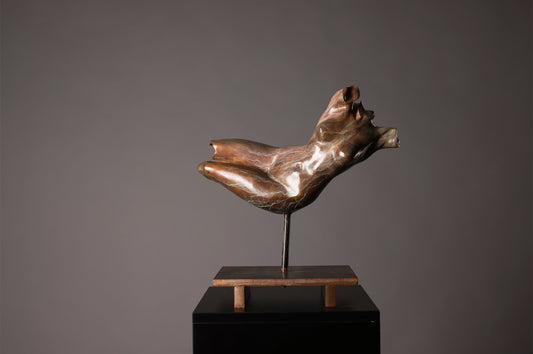 Bronze sculpture of a nude figure on a gray background