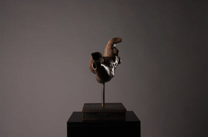 Abstract sculpture on a dark pedestal against a gray background