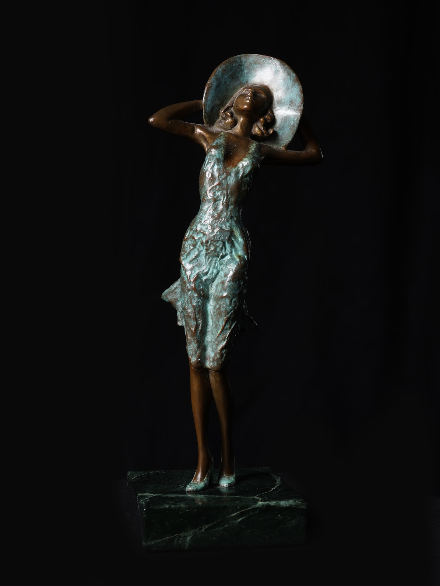 Bronze sculpture of a woman holding a disc on a black background
