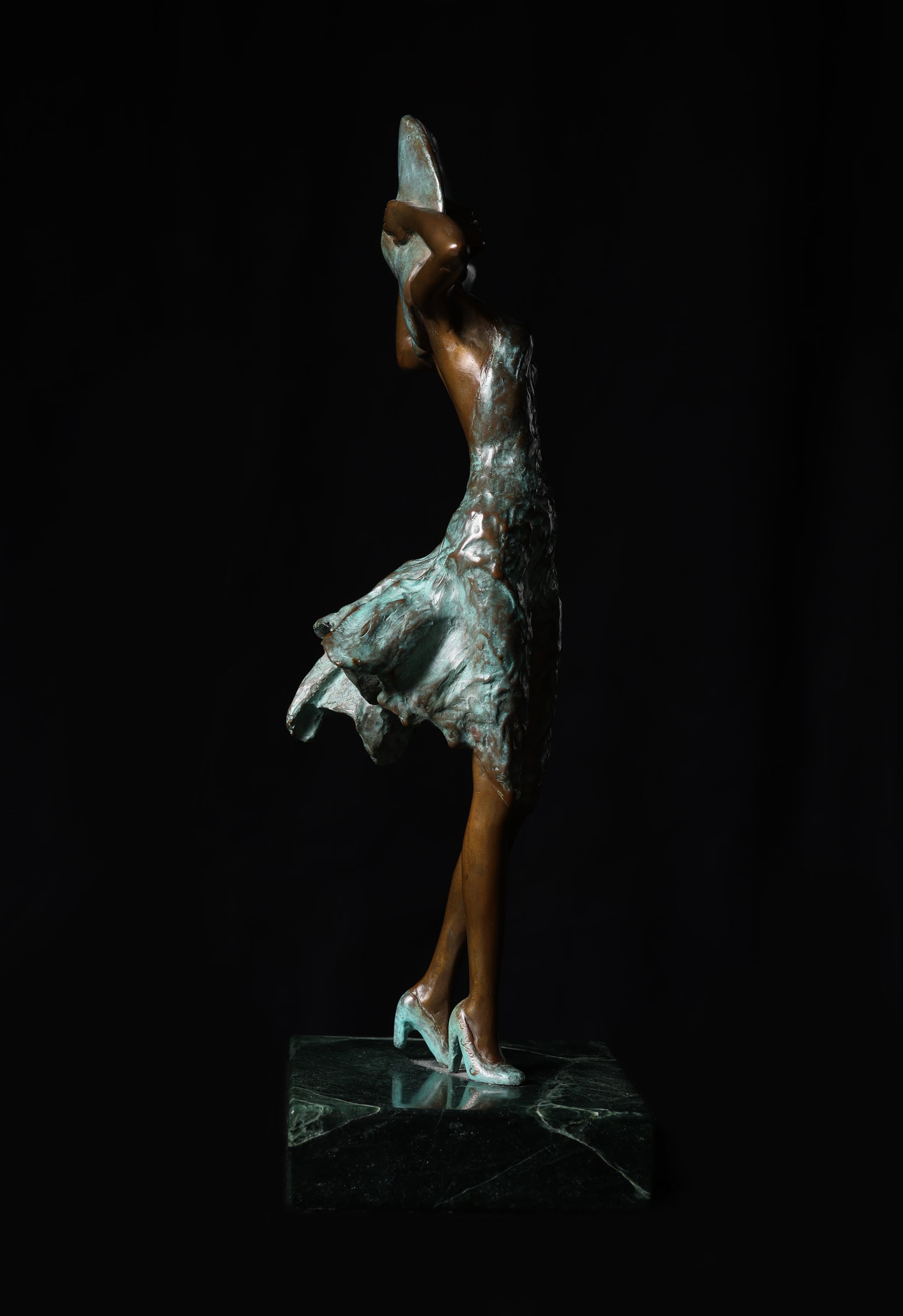 Bronze sculpture of a dancer with a silver skirt on a black background
